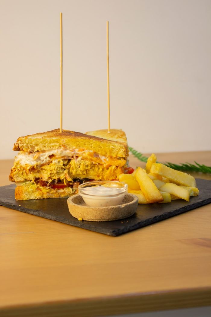 Sándwich club con pollo, bacon y patatas fritas caseras.